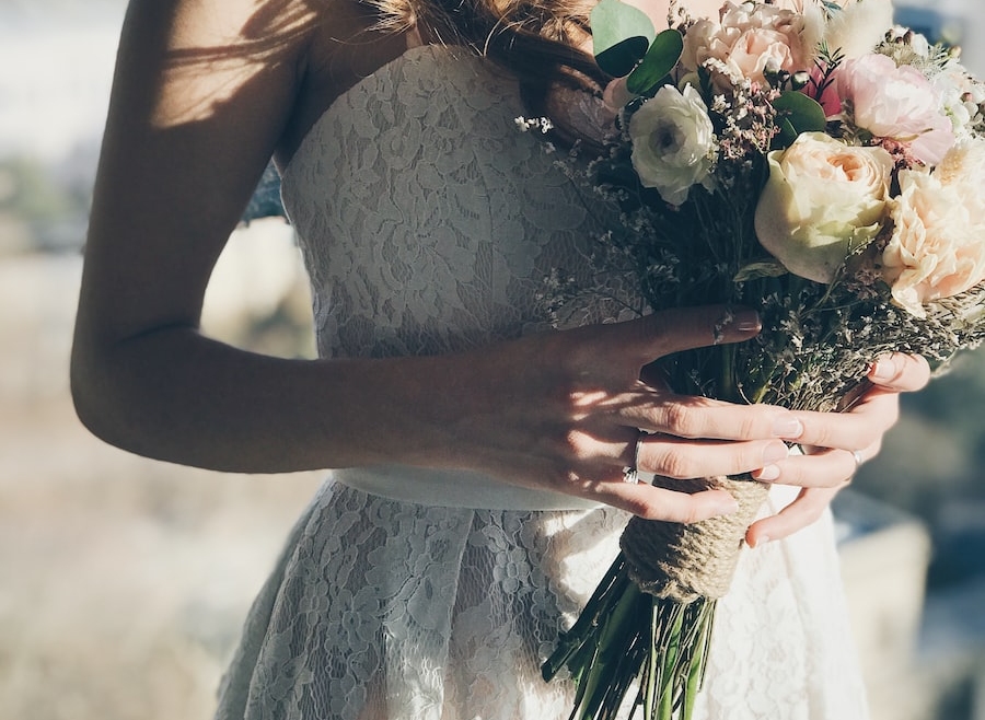 woman in white floral strapless dress holding flowers