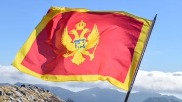 a flag on top of a mountain with mountains in the background