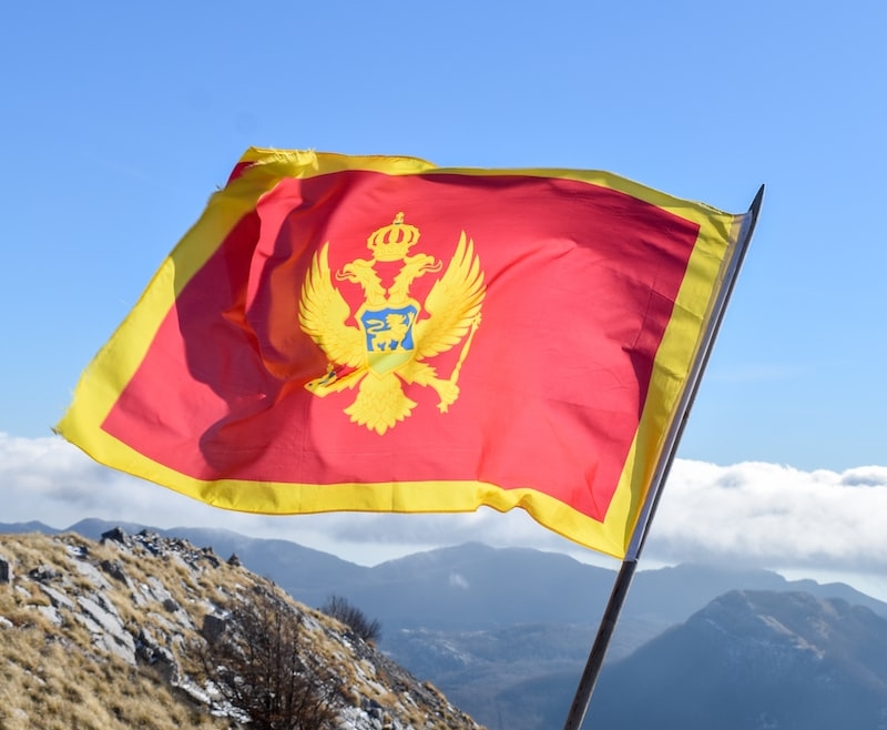 a flag on top of a mountain with mountains in the background