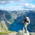 man standing on rock looking towards lake