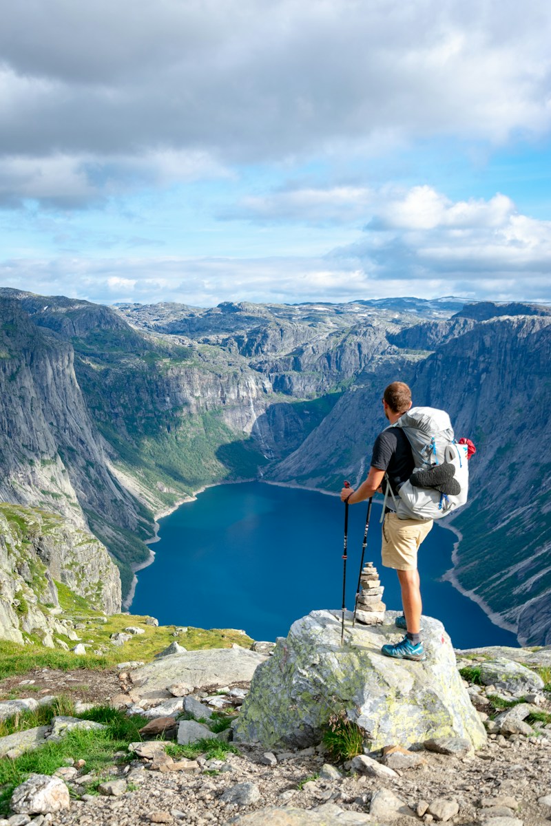 man standing on rock looking towards lake