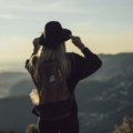 woman in gray hoodie and black pants wearing black hat standing on top of mountain during