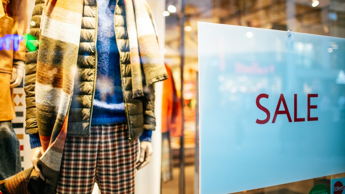 a mannequin in a window display with a sale sign