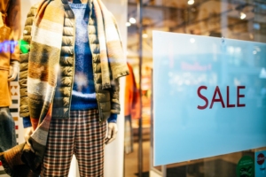 a mannequin in a window display with a sale sign