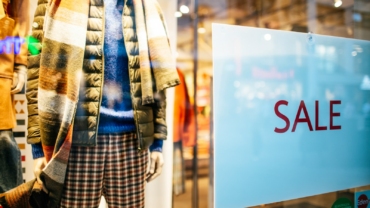 a mannequin in a window display with a sale sign