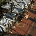 A group of people sitting under umbrellas on a sidewalk