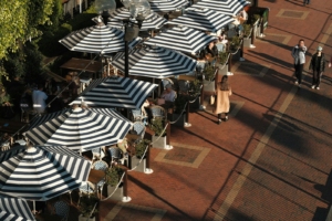 A group of people sitting under umbrellas on a sidewalk