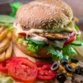hamburger with vegetables and meat beside French fries